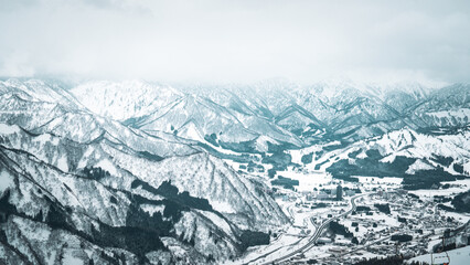 Obraz premium A breathtaking panoramic view of snow-covered mountain ranges including Ishiuchi Maruyama, Yuzawa Kogen, and distant peaks near Echigo-Yuzawa in Niigata, Japan, captured from Gala Yuzawa station.