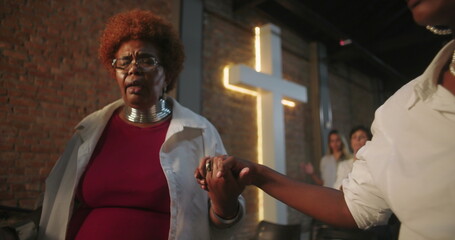 Close-up of participants in prayer, holding hands during church service, guided by leader in modern...