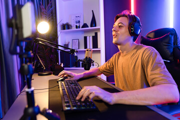 Host channel of gaming smart streamer playing online game to be winner, wearing headphone with viewers live steaming on media social online for selected team competition at neon light room. Pecuniary.