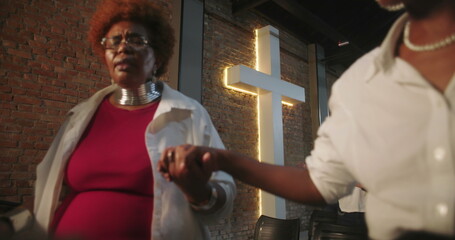 Close-up of participants in prayer, holding hands during church service, guided by leader in modern...