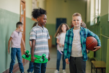 Obraz premium Students walking in school hallway holding skateboard and basketball