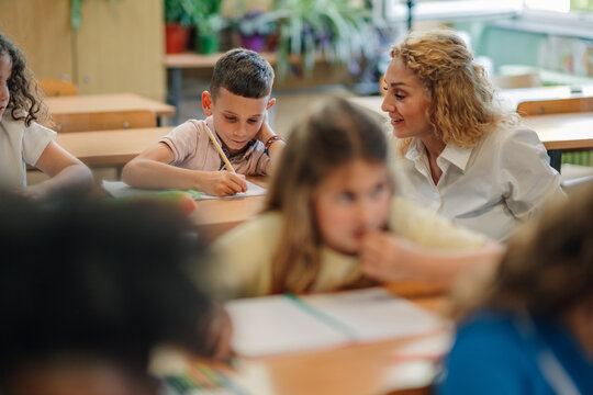 Teacher helping pupil during class in elementary school