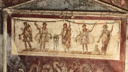 Pompeii, Italy - 8 January 2025. A detailed fresco depicts a ritual procession with five lares figures in tunics holding offerings and garlands, centered around a smoking altar.
