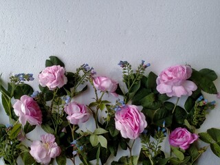 pink roses with green leaves and small blue flowers on a white background