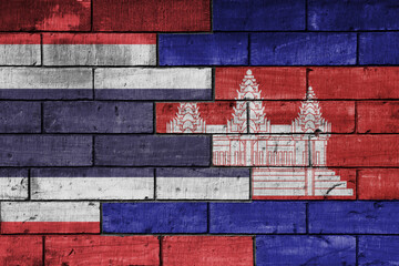 colourful painted big national flag of cambodia and flag of thailand on a massive old brick wall background. concept