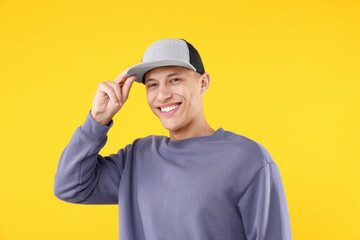 Young man wearing stylish baseball hat on yellow background