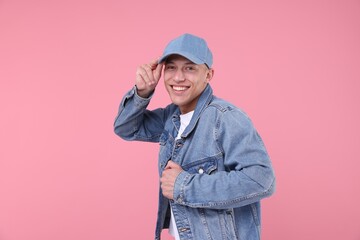 Young man wearing stylish denim baseball hat on pink background