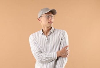 Young man in stylish baseball hat on beige background