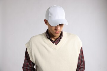 Young man in stylish baseball hat on light grey background