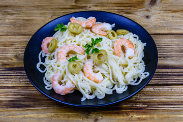 Italian pasta with shrimps and olives in a black plate