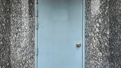 The blue door outside the building, the building walls are covered with shiny black granite tiles, which is the background of the building walls.