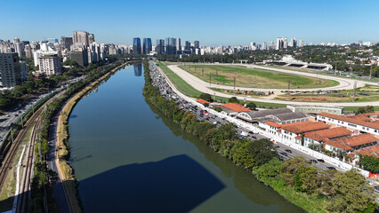 Visão aérea da Marginal Pinheiros em São Paulo com intenso tráfego, prédios comerciais e o rio...