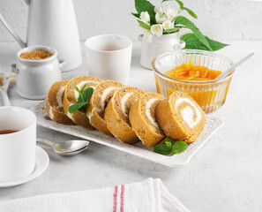 Baked pumpkin roll on a white plate with pumpkin puree of focus in the background in a breakfast kitchen scene