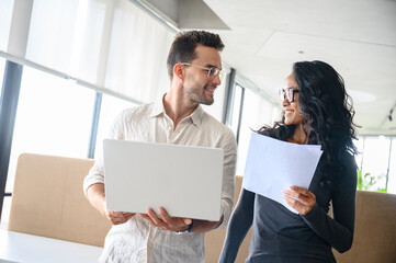 Young Professionals Collaborate In Sunlit Modern Office Space While Reviewing Documents