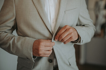 Le marié qui met sa veste de costume juste avant son mariage