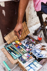 Artist or painter hands on the street painting on the sidewalk using paints and brushes to draw in street art style.	