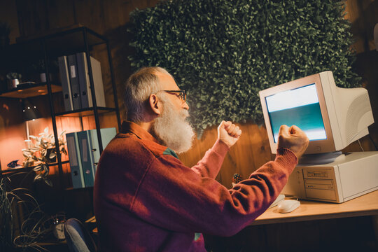 Enthusiastic elderly man engaging with technology, showcasing programming and coding skills on a vintage computer setup
