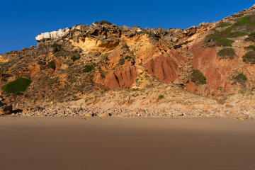 Telheiro beach at sunset in Sagres, Portugal, with its colorful cliffs.