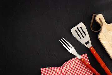 Stainless steel utensils and red picnic napkin, top view. Barbecue utensils