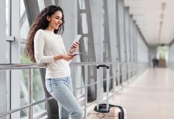 Portrait Of Beautiful Young Woman Using Smartphone While Waiting At Airport, Happy Smiling Middle...