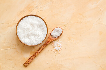 Coarse sea salt in a wooden and spoon, top view. Salt for spa, salt baths or cooking
