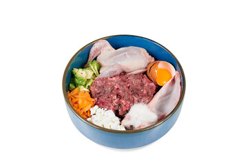 Natural dog food. Raw meat food, vegetables, egg in bowl on white background, top view. 