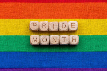 Colorful pride month celebration with wooden block letters on rainbow flag