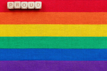 Proud wooden blocks on rainbow stripes representing lgbtq+ pride and equality
