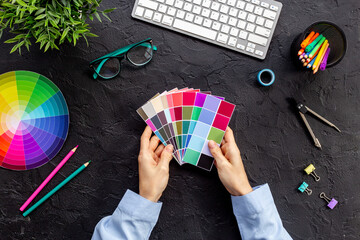 Creative designer hold color paint swatches in hands, top view. Decorator workspace concept