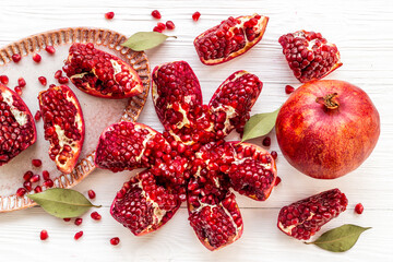 Fresh ripe pomegranate with cut in half and pieces on plate to eat, top view.