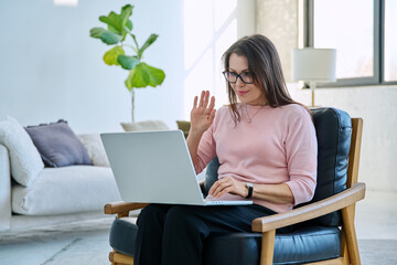 Middle aged woman working remotely, video conference, using laptop