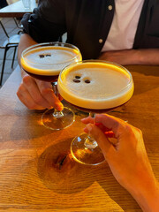 Hands Clinking Espresso Martinis at Golden Hour in Cozy Caf&eacute; Setting