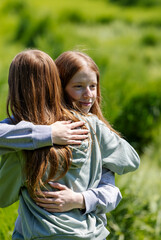Sisters embrace in green field during warm, sunny day