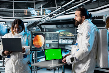 Astronaut checks green screen tablet interface before landing spaceship on Mars. Crew members looking at chroma key device during mission to red planet surface, testing human survival in deep space