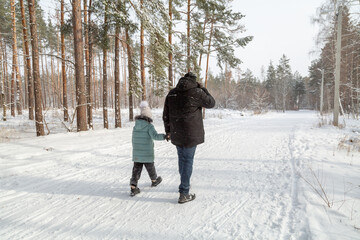 Dad and daughter walking and having fun in snowy winter forest