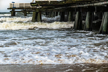 Beautiful old wooden pier and stormy sea waves