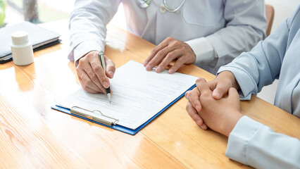Male doctor with stethoscope explaining treatment and giving recommendation to patient while he is writing symptom