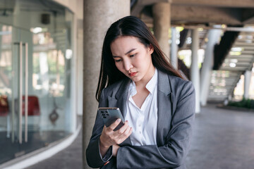 Asian businesswoman in suit, feeling stress and using smartphone to reading text message for reply...