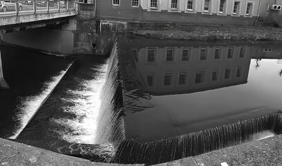 Monochrome image. City dam. Reflection of architecture in the mirror surface of water
