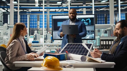 Shareholders reading documents, discussing investment opportunities in clean energy manufacturing. Executives in solar panels plant office reviewing solar technology paperwork reports, camera A