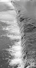 Vertical, black and white image. River mountain rapids. Dynamic composition. Abstract forms