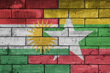 colourful painted big national flag of kurdistan and flag of myanmar on a massive old brick wall background. concept