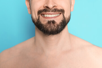 Smiling man before shaving on light blue background, closeup