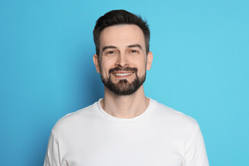 Smiling man before shaving on light blue background