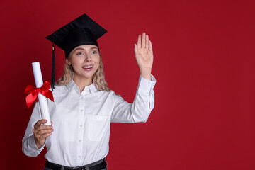 Happy student with diploma waving after graduation on red background. Space for text