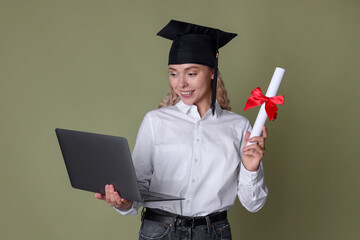Happy student with diploma and laptop after graduation on green background