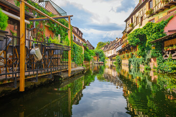 Water level view from a boat as it passes by half timbered colorful historic buildings along the Lauch Canal in the historic Petite Venise district of Colmar, France.
