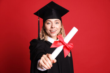 Happy student with diploma after graduation on red background, selective focus