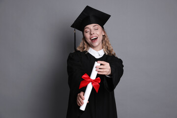 Happy student with diploma after graduation on grey background
