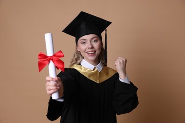 Happy student with diploma after graduation on beige background, selective focus